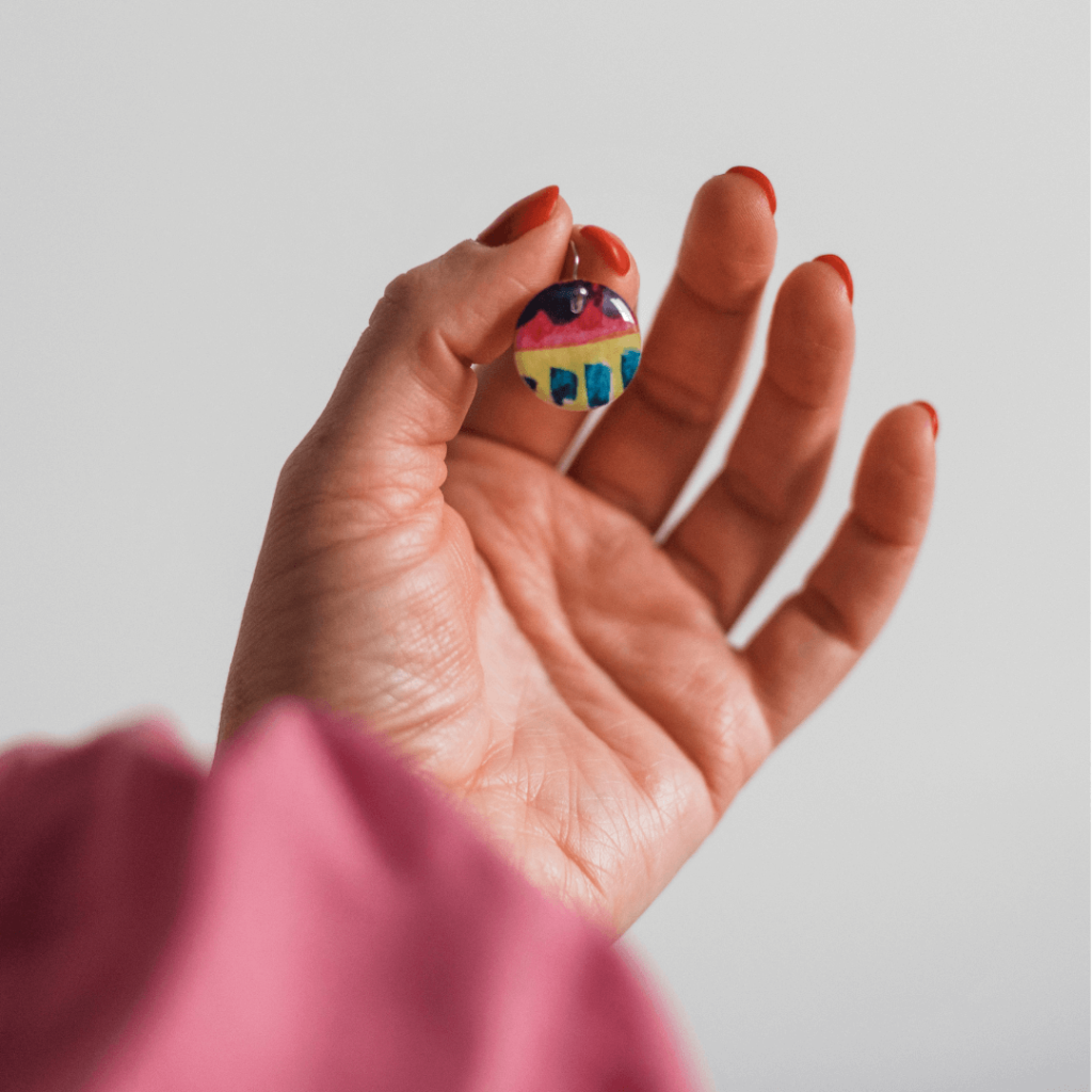 Kolczyk z akwareli wiszący trzymany w ręce